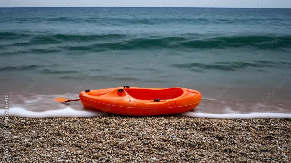 A bright orange kayak sits on a sandy beach, gently washed by calm waves under a clear blue sky along the coastline A bright orange kayak sits on a sandy beach, gently washed by calm waves under a clear blue sky along the coastline