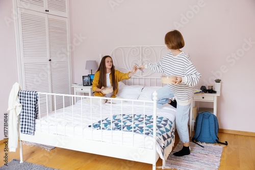 Teenage girl giving fork to friend on bed before they having lunch photo