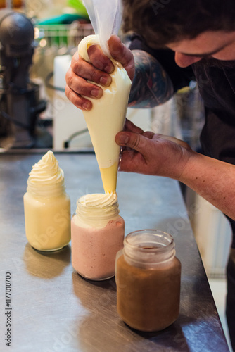 Barista at cafeteria preparing milkshakes with whipped cream on top photo