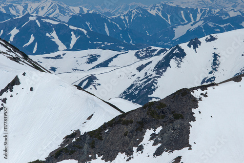 Aerial view of the snow-covered mountains in the Magadan region of Russia. Winter landscape of the mountains. Air travel to the far north of Russia. Nature of Siberia and Russian Far East.