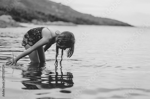 Tween girl playing alone in the water of Coles Bay in Tasmania