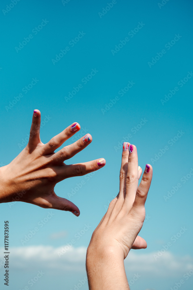 Hand manicure with colorful nails over blue sky Hand manicure with colorful nails over blue sky