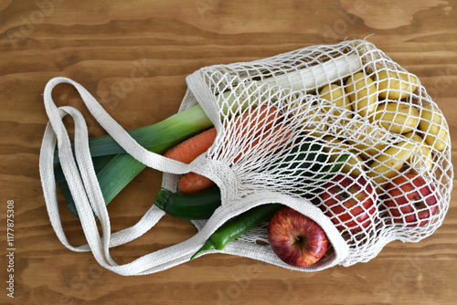 Reusable mesh bag with groceries on wooden background