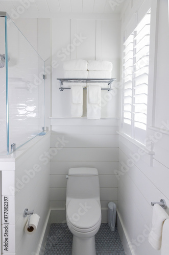 Plush white Towels on Shelf in home with toilet  photo