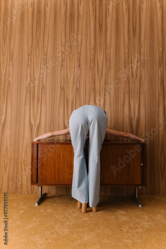 Person Leaning Over Wooden Cabinet in a Relaxed Pose photo