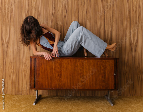 Young Woman Posing Creatively on Vintage Wooden Cabinet photo