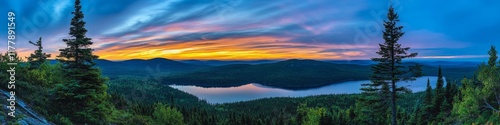 Serene sunset over a tranquil lake surrounded by lush forests and distant hills.