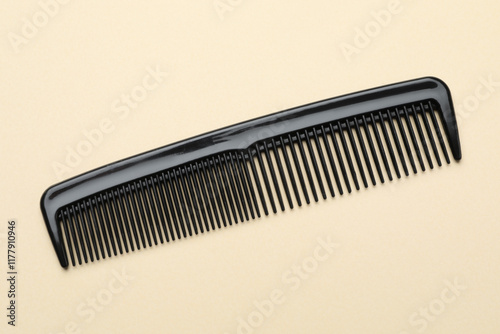 One black plastic comb on beige background, top view