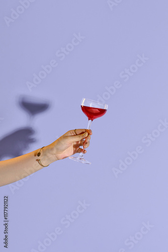 Young girl holding glass of tasty red wine on blue background.