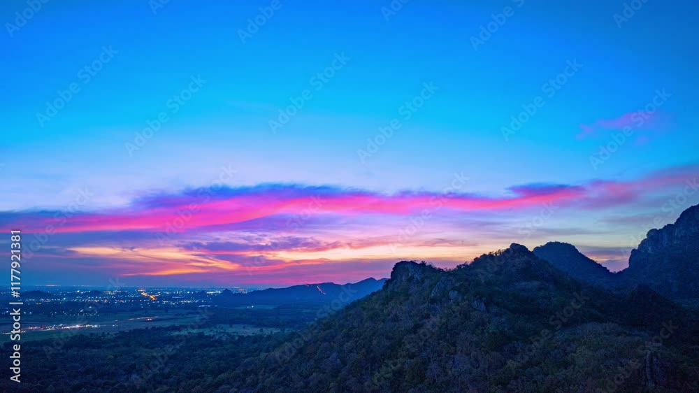 A panoramic view of dramatic mountain peaks silhouetted against a vibrant sunset sky, with fiery hues of red, orange, and pink blending into the fading blue. sunflowers fields around the mountains. A panoramic view of dramatic mountain peaks silhouetted against a vibrant sunset sky, with fiery hues of red, orange, and pink blending into the fading blue. sunflowers fields around the mountains.