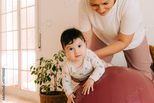 Mother playing with a baby on exercise ball in the living room  photo