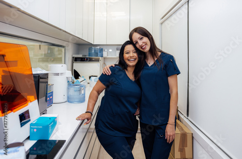 Smiling Dental Hygienists Hugging in a Modern Clinic Setting photo