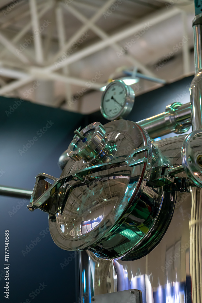 Obraz premium Close-up view of large shiny metal tank in food processing factory. Milk, juice, beer or wine production line. Soft focus. Modern industrial equipment theme.