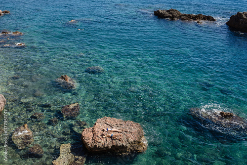A couple sunbathe on a sea rock after swimming