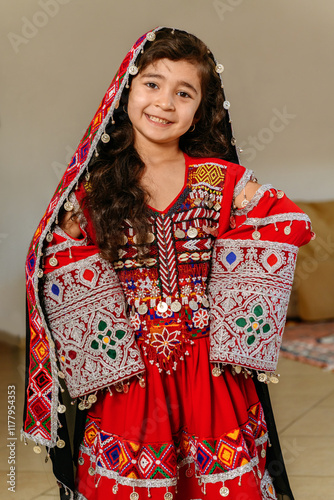 Smiling afghan girl showing a traditional dress at home photo