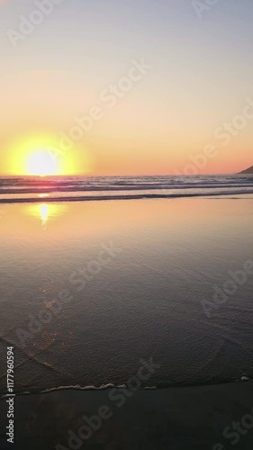 Golden sunlight illuminating serene Lofoten beach, midnight sun casting warm glow over reflective waters with majestic mountain silhouette during tranquil Norwegian summer evening