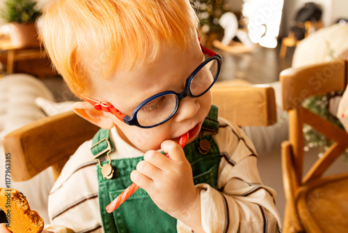 A child with orange hair is eating a lollipop.  photo