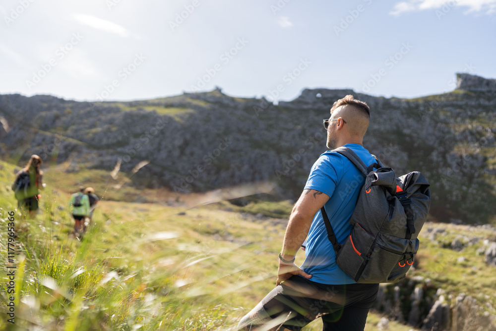 Male hiker resting while hiking in the mountains with friends Male hiker resting while hiking in the mountains with friends