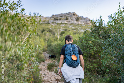 Hiker walking up mountain trail with backpack and dog photo