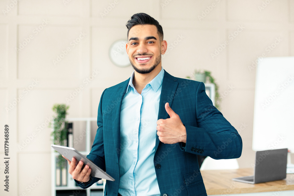 Smiling Arab businessman holding computer, showing thumb up gesture in office. Handsome guy entrepreneur recommending online services, having virtual conference with colleagues Smiling Arab businessman holding computer, showing thumb up gesture in office. Handsome guy entrepreneur recommending online services, having virtual conference with colleagues