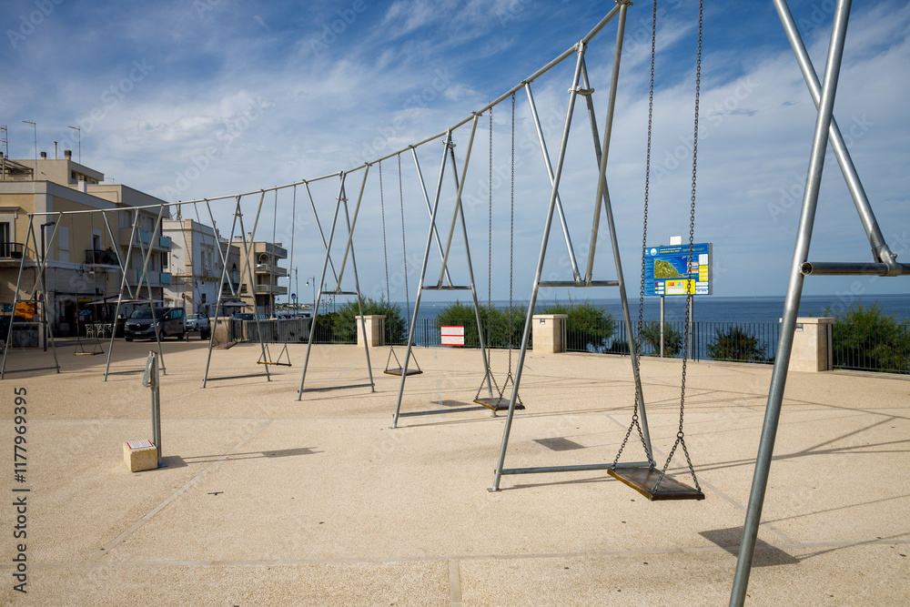 Fototapeta premium Swing on a metal chain on an empty embankment. Center of the Polignano a Mare village, in province of Bari.