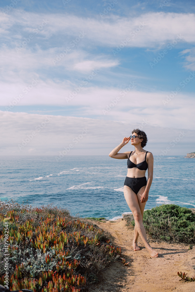 Woman in Swimwear Standing on Coastal Cliff Overlooking Ocean Woman in Swimwear Standing on Coastal Cliff Overlooking Ocean