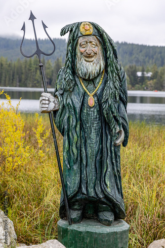 Štrbské Pleso, wood carving in front of mountain lakes in autumn colours, high tatra, slovakia photo