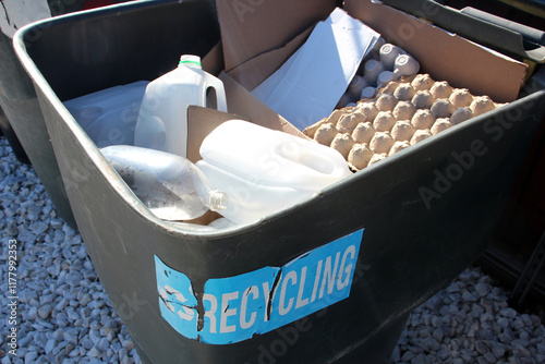 Recycling bin filled with cardboard and plastic waste outdoors. photo