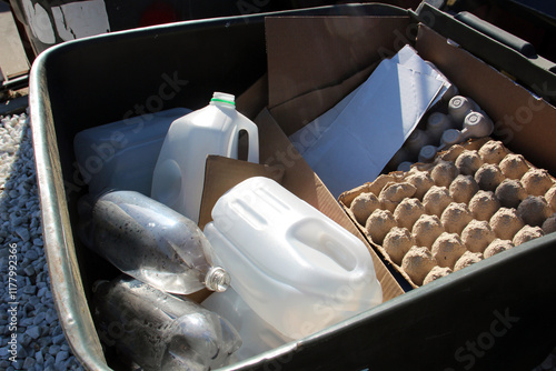 Recycling materials including plastic bottles, cartons, and cardboard in a bin.