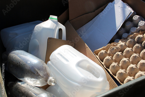 Recycling materials including plastic bottles, cartons, and cardboard in a bin.
