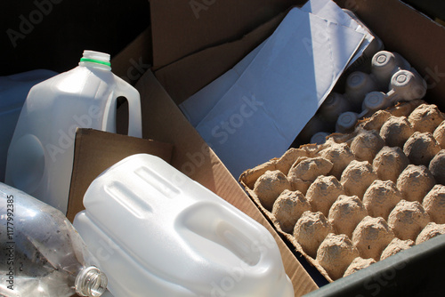 Recycling materials including plastic bottles, cartons, and cardboard in a bin.
