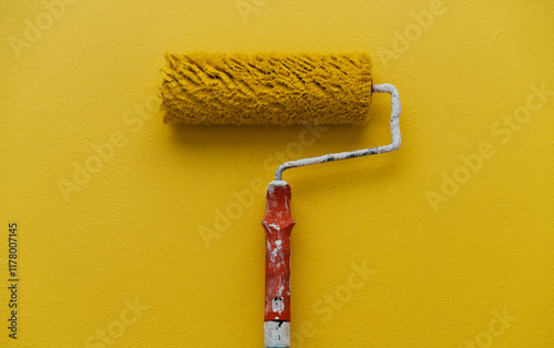 A paint roller rests on a Yellow wall