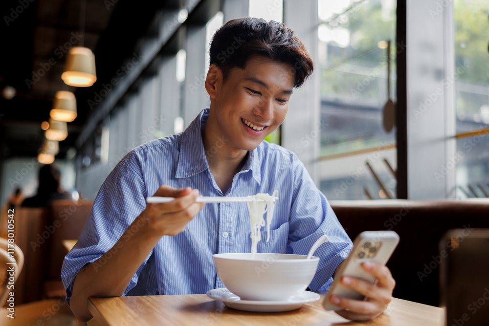 Happy man using mobile phone while eating noodles in cafe Happy man using mobile phone while eating noodles in cafe