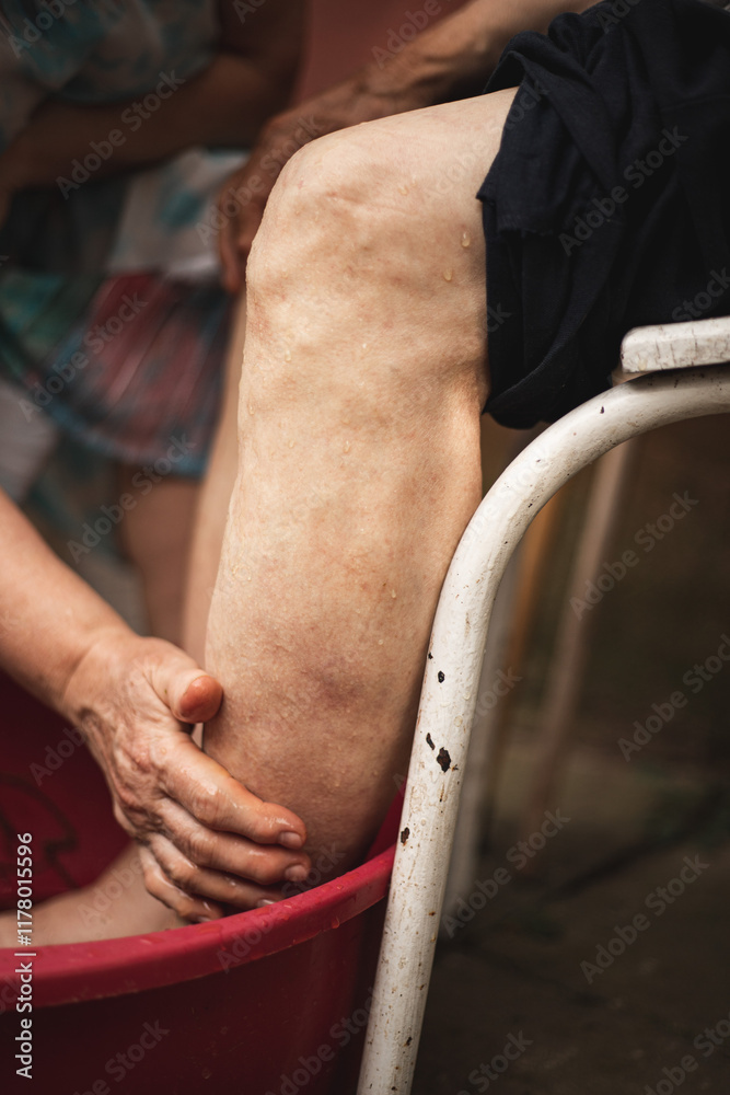 Obraz premium Caring for an elderly person. Washing feet. Nurse. Love for old relatives. Washing with herbal decoction. Useful folk care.