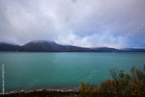 Autumn landscape of the Lyngen Alps in Northern Norway with snowy peaks, dramatic clouds, and a tranquil fjord. photo