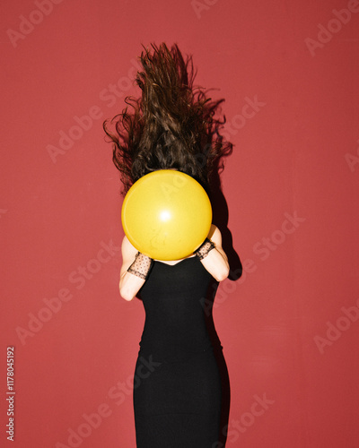 Woman Holding Yellow Balloon Against Red Background with Hair Fl photo