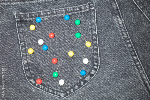 Close-up of jeans with colourful office supply paper pins on a pocket photo