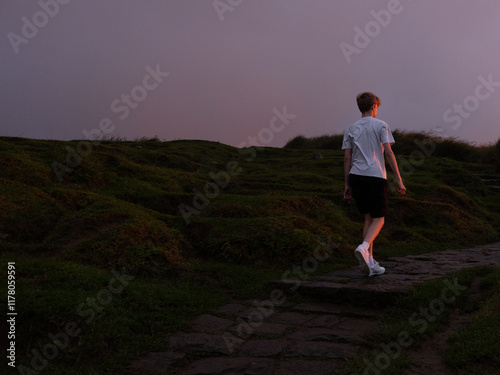 Boy walks towards setting sun. Copyspace behind him. photo