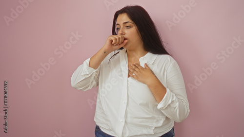 Curvy woman feeling unwell against an isolated pink background with her hand on her chest and touching her mouth