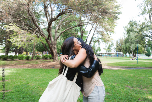 Young latina best friends hugging in the park