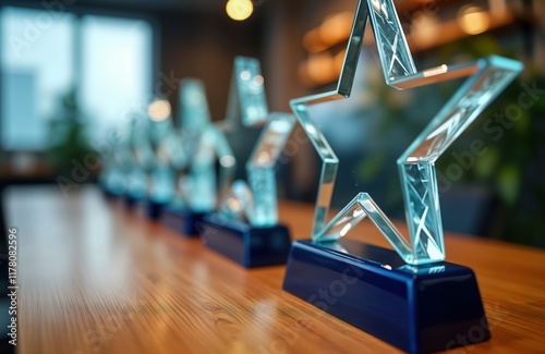 Corporate award trophies are displayed on light brown wooden table. Glass star-shaped trophies are arranged in row. Recognition, achievements are highlighted. Pro success, competitions are symbolized.