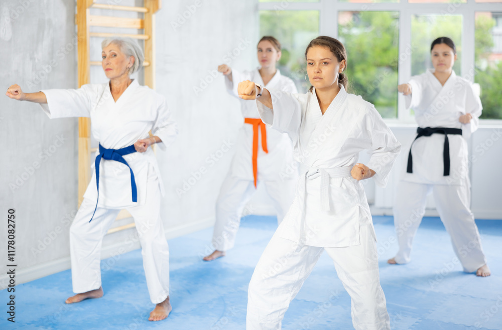 Women of different ages in kimono trying new martial moves at karate class Women of different ages in kimono trying new martial moves at karate class