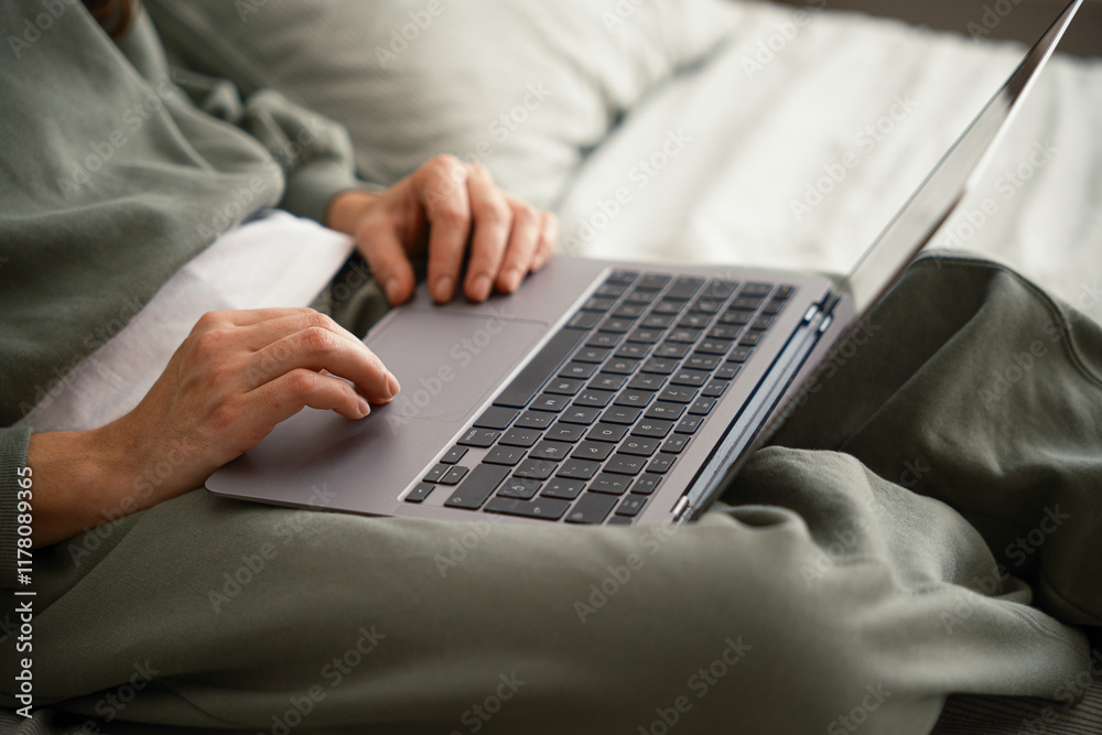 Crop of woman using laptop in bed Crop of woman using laptop in bed