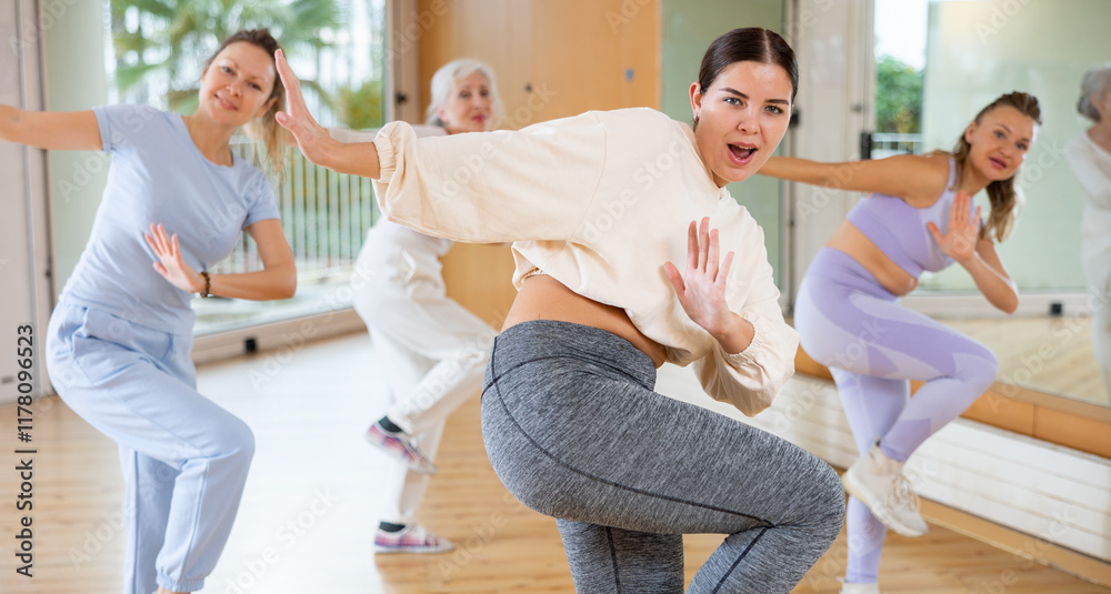 Fototapeta premium Active young woman practicing fitness dance in training hall during dancing-classes. Women training dance in hall
