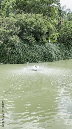 water fountain in a park during a sunny day with a rustic wall and green scenery in the background