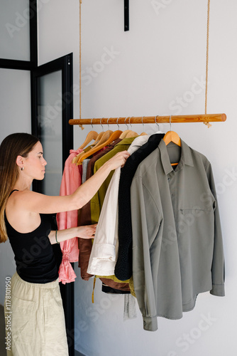 Lady selects a jacket from her closet as she prepares to go out photo
