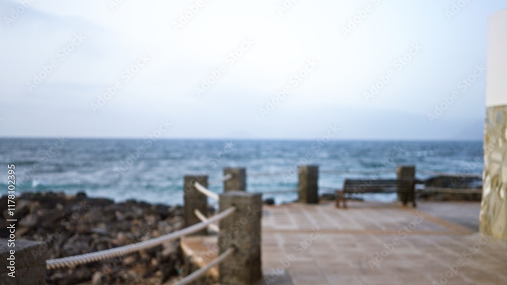 Obraz premium Blurry ocean view with bokeh effect in lanzarote, spain showcasing an outdoor terrace near the atlantic ocean in the canary islands with a defocused stone railing and bench.