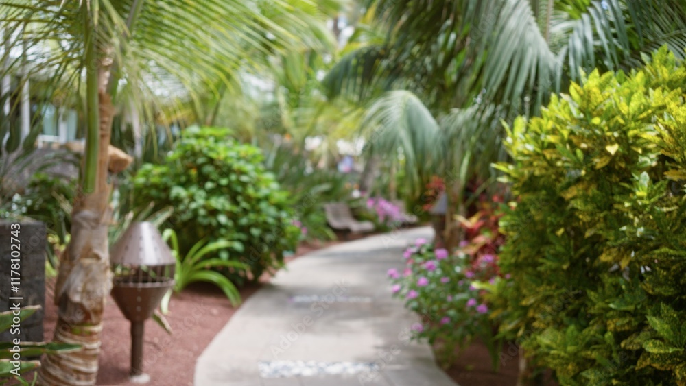 Fototapeta premium Blurred tropical resort path with lush green foliage and defocused background, evoking relaxation and vacation vibes.