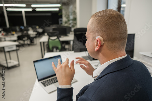 Caucasian deaf man communicates in sign language on laptop in office. 
