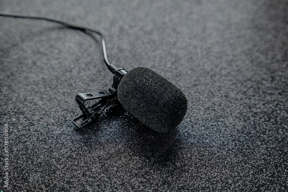 Compact coloured tie clip microphone for interviews with pop filter on black glossy background. Concept: Audio, professional sound, sound.